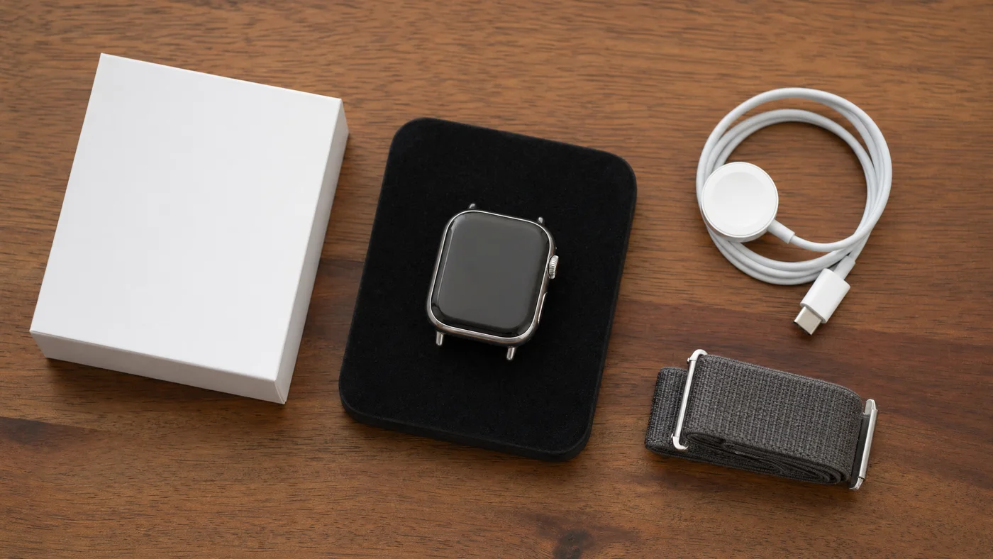 Apple Watch本体と純正バンド、充電ケーブル、元箱が並ぶ机のイメージ