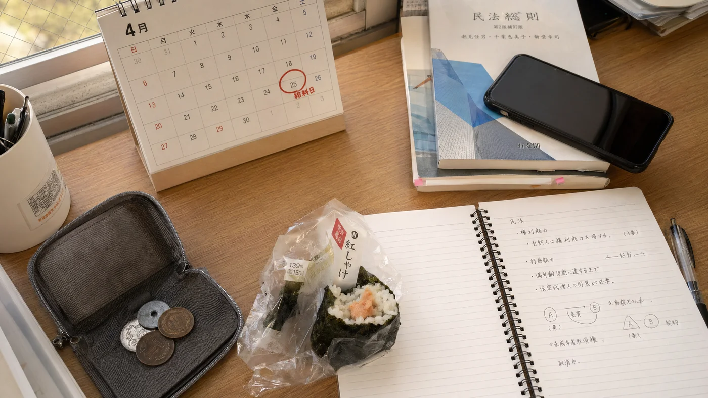 学生がバイト代日までの日数を確認している机のイメージ