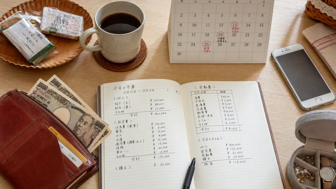 家計のやりくりに使う家計簿と財布、急な出費を考える場面